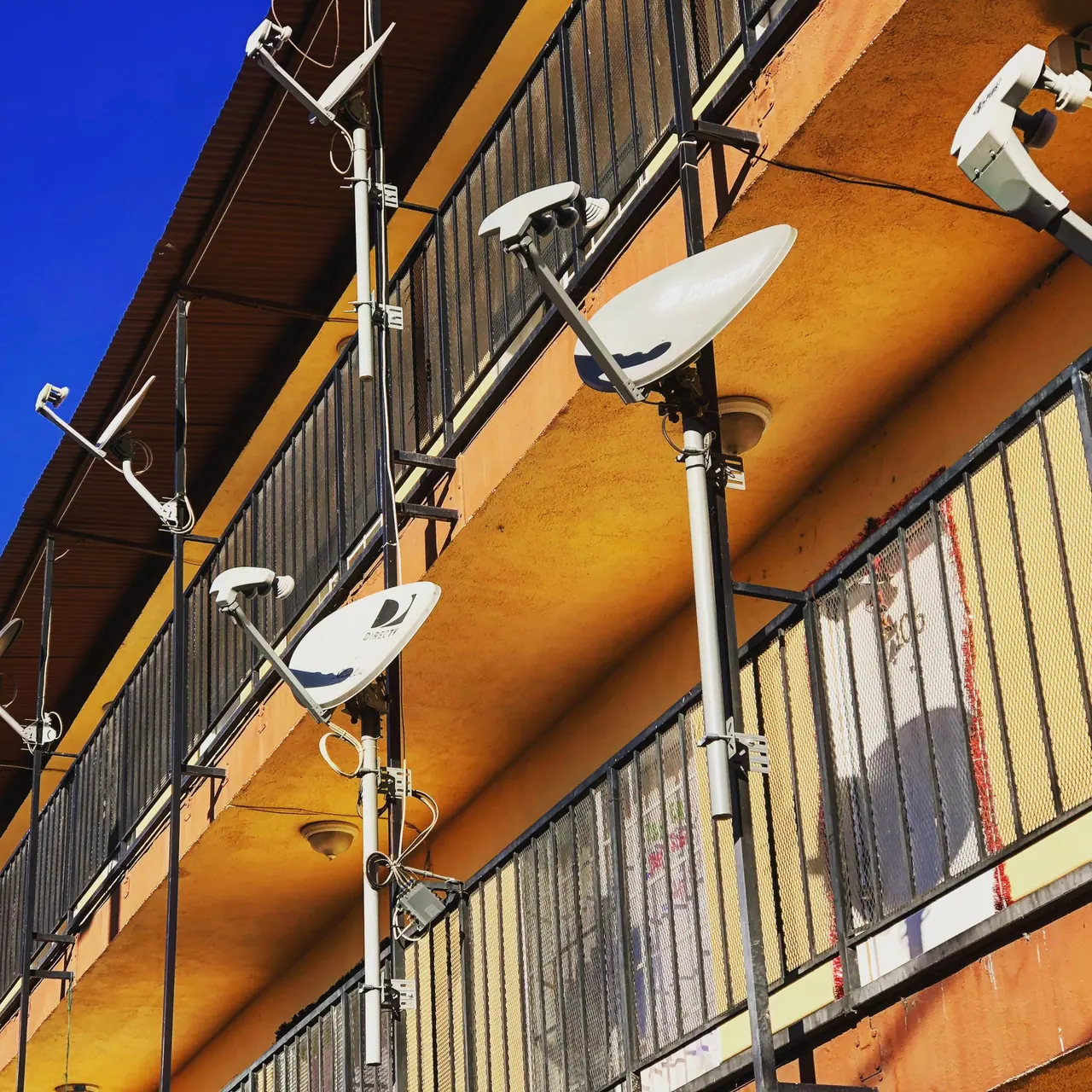 Satellite dishes along an apartment facade.