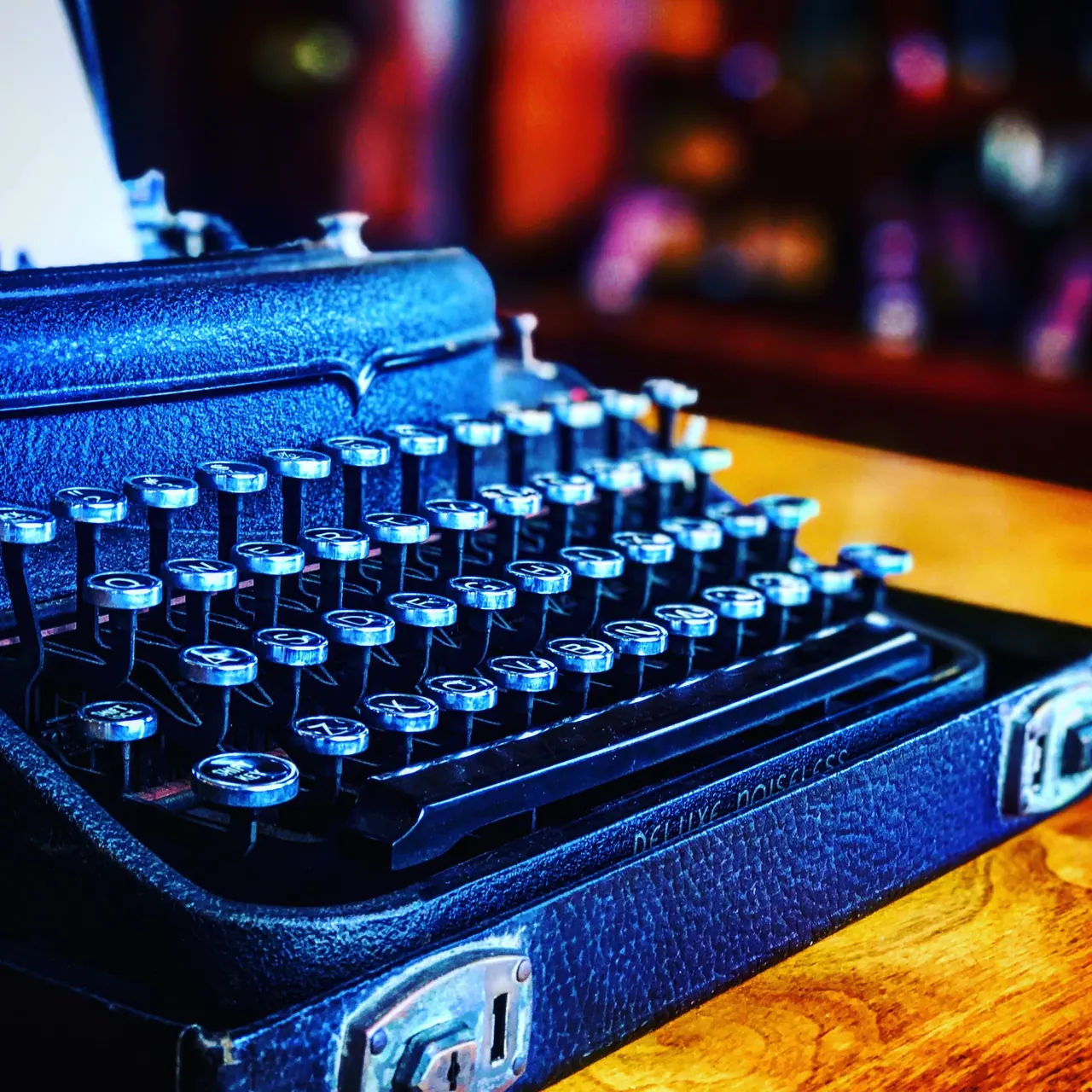 A blue manual typewriter on a wooden counter.