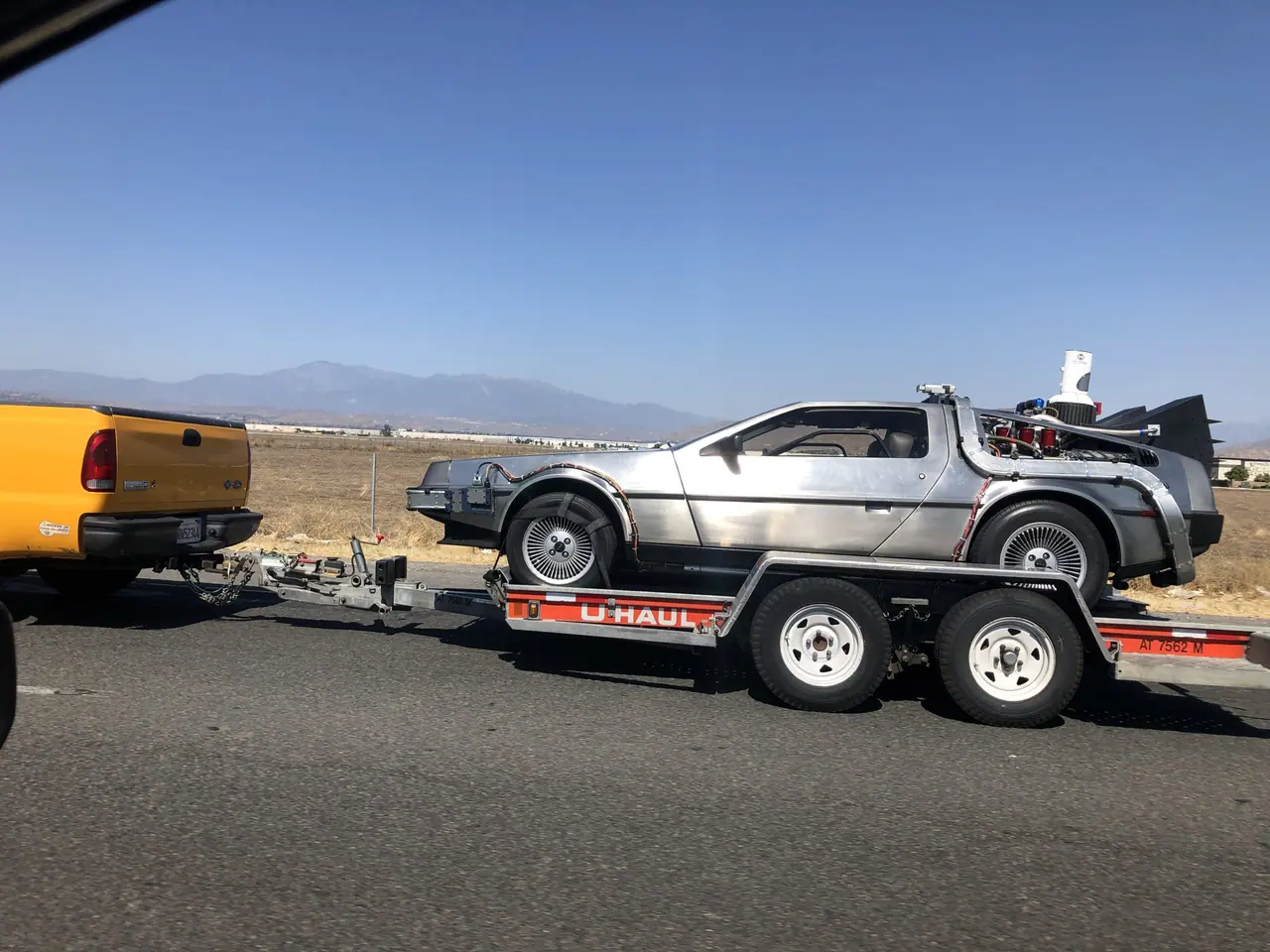 A DeLorean time-machine replica traveling on a trailer.