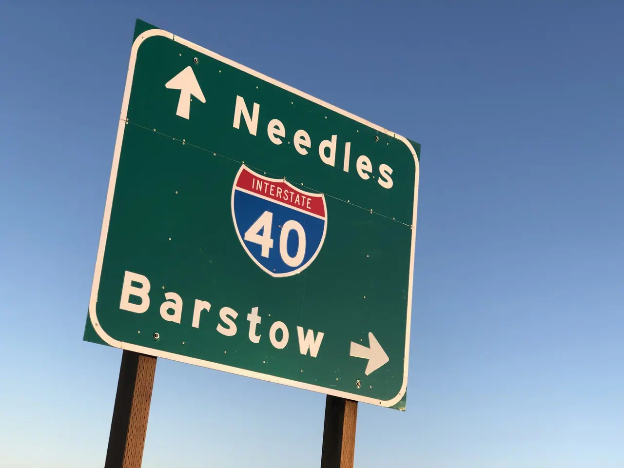 A desert highway sign pointing toward Needles and Barstow.