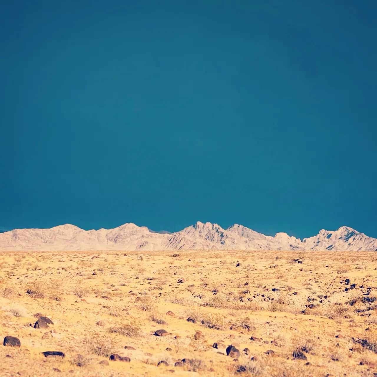 Sunlit desert ridges beneath a deep blue sky in Death Valley.