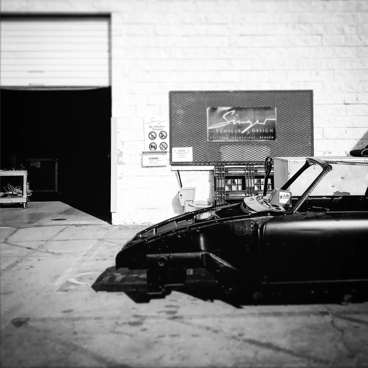 A stripped car body outside a Porsche workshop.