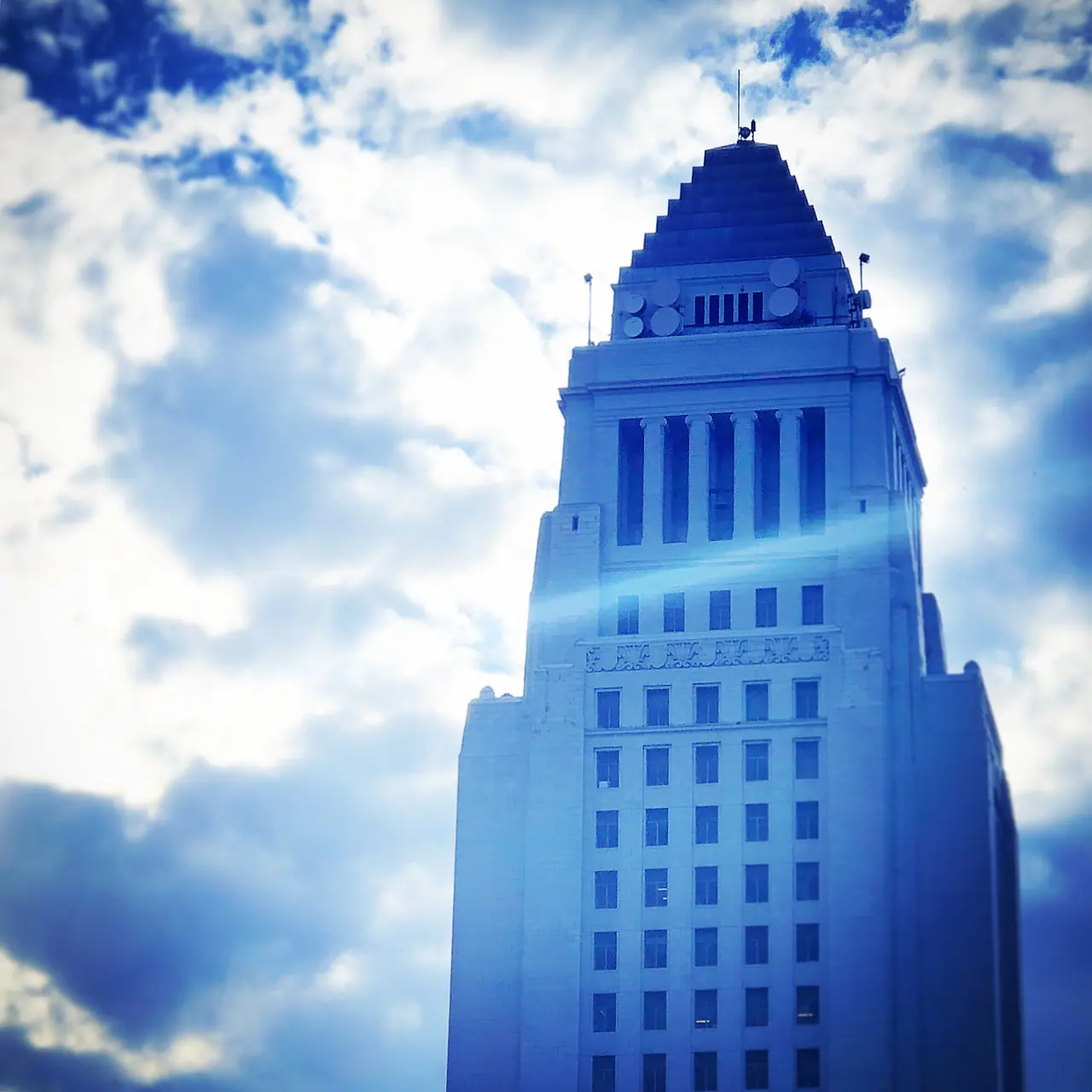 Los Angeles City Hall framed by bright clouds.