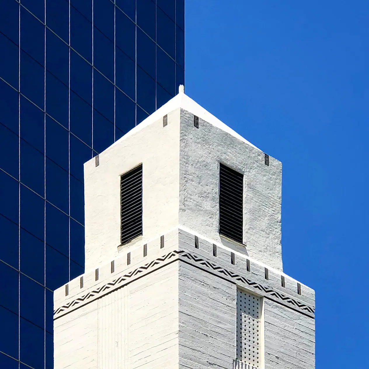 A pale building corner beside a blue glass facade.