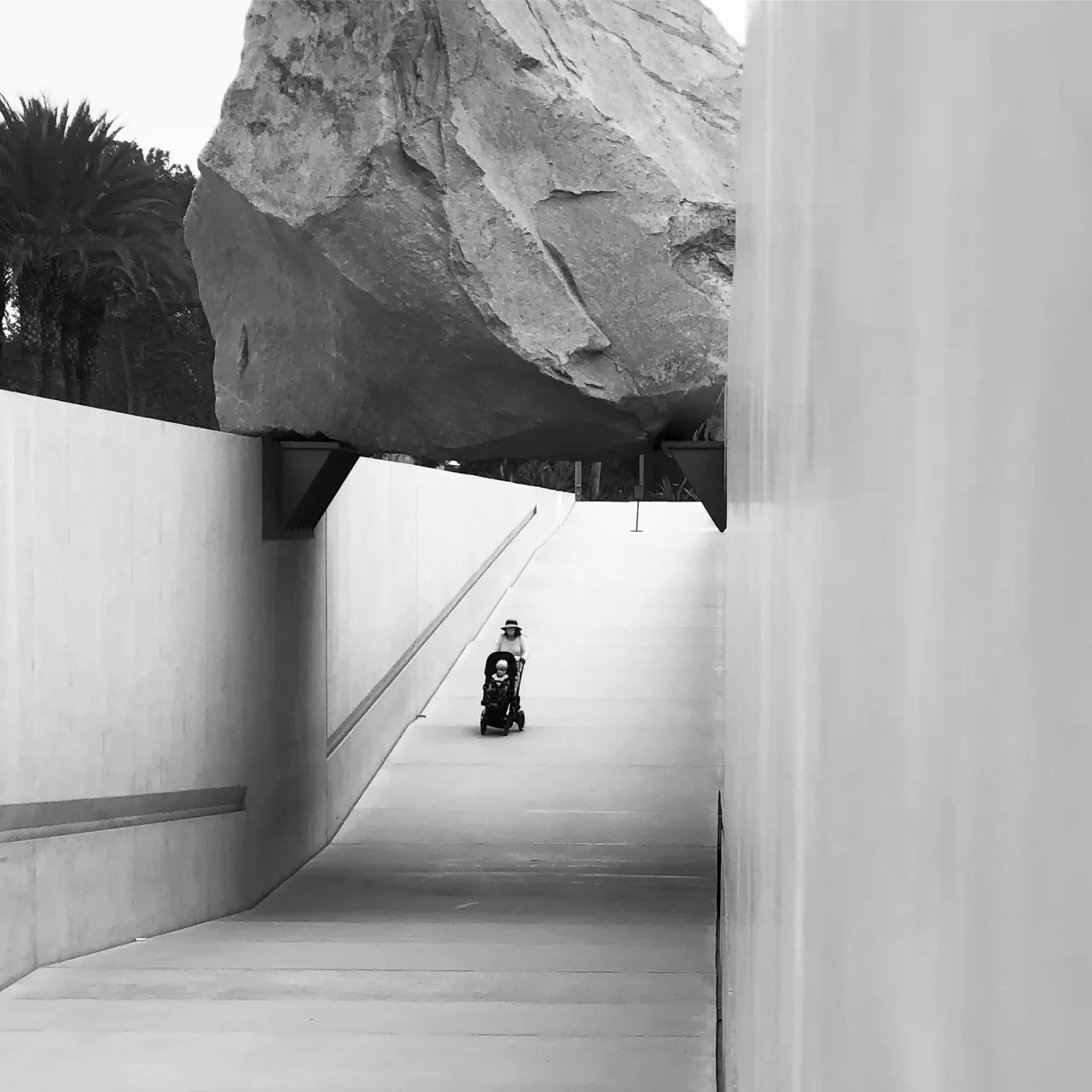 A visitor beneath the suspended boulder at LACMA.
