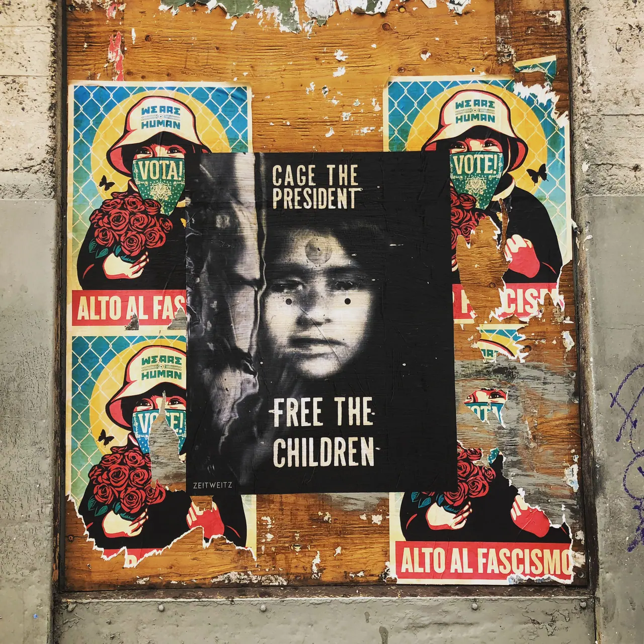 Protest posters layered on a city wall.