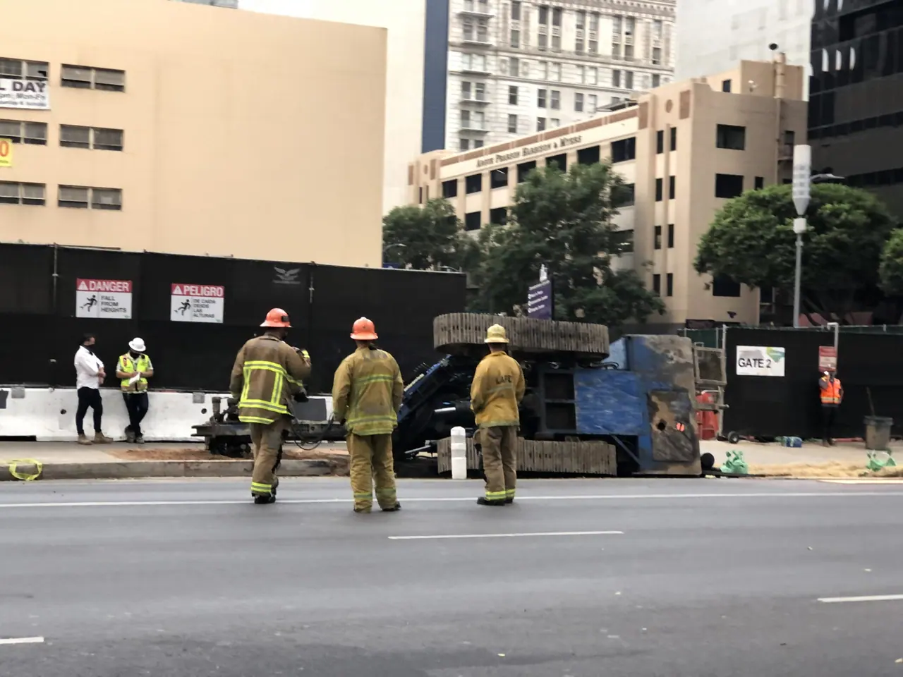 Firefighters beside overturned construction equipment.