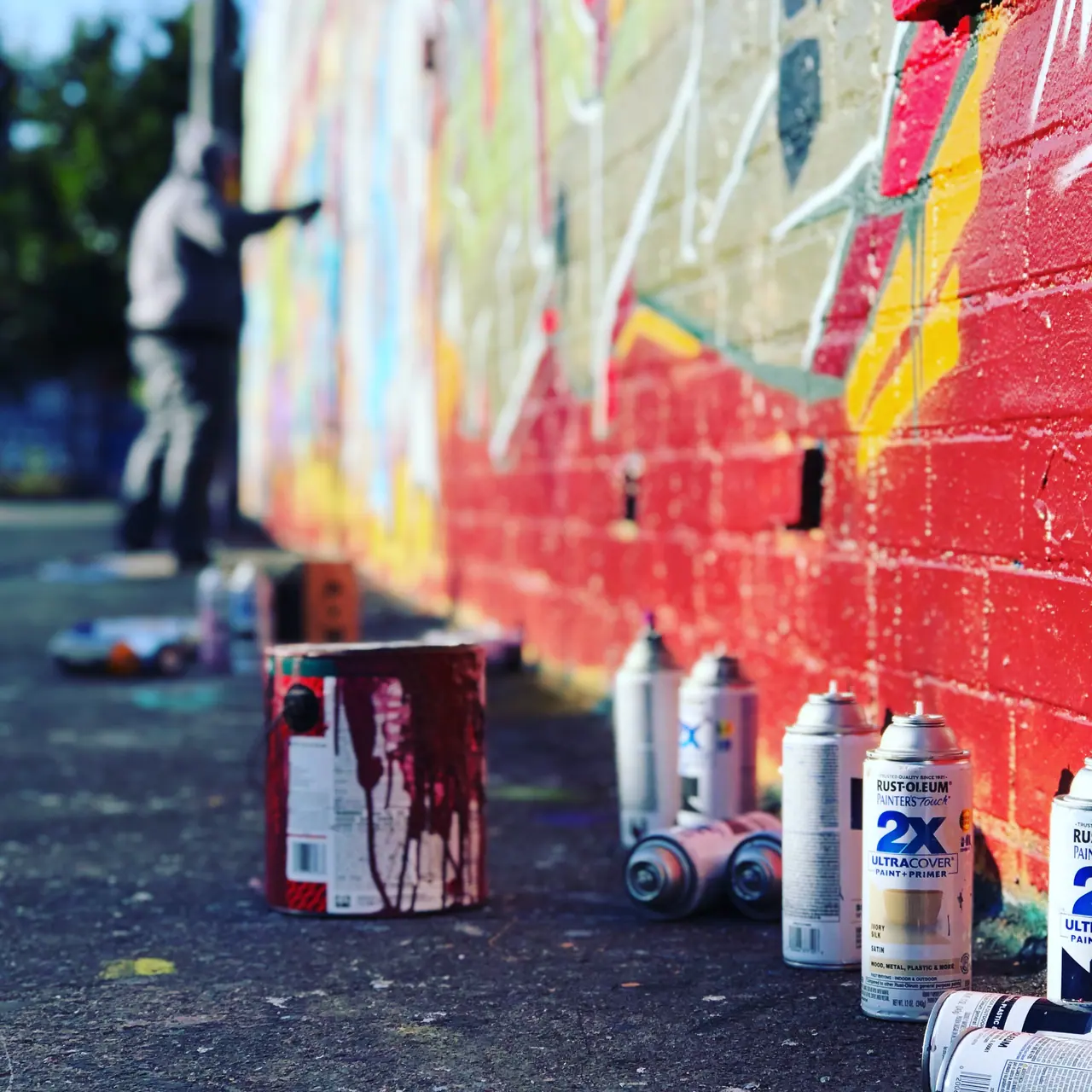 Spray cans beside a mural in progress.