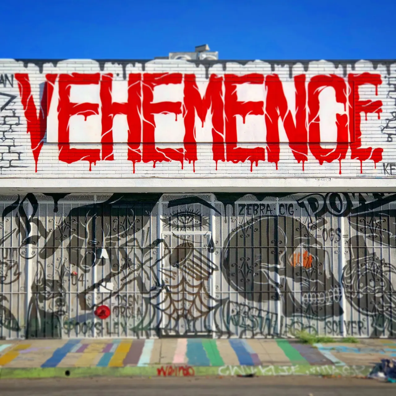 Bold red lettering above a mural-covered storefront.