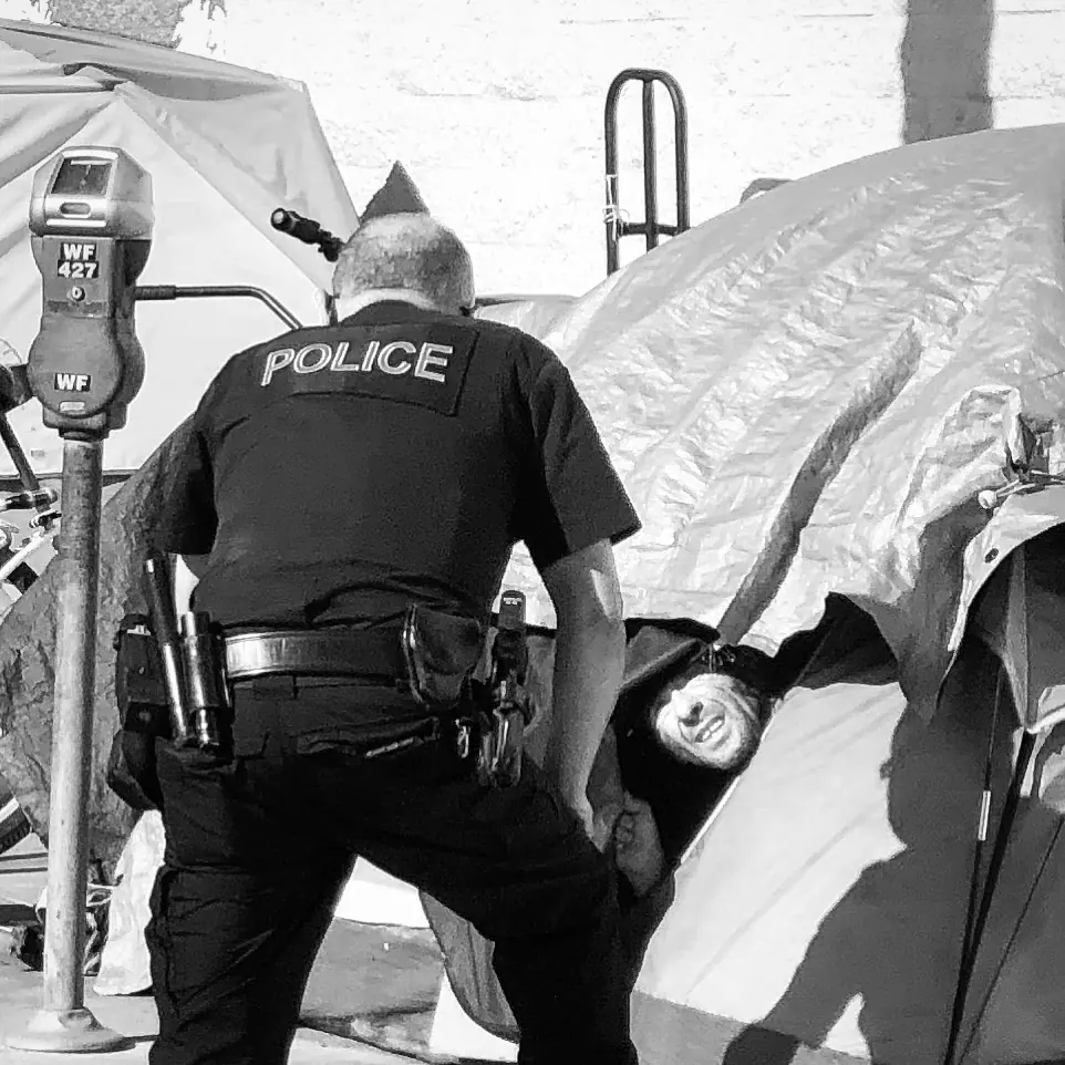 A police officer beside a sidewalk tent.