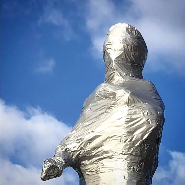 A wrapped statue beneath a cloudy sky.