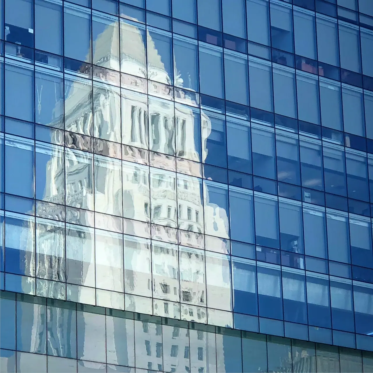 Los Angeles City Hall reflected in a glass facade.