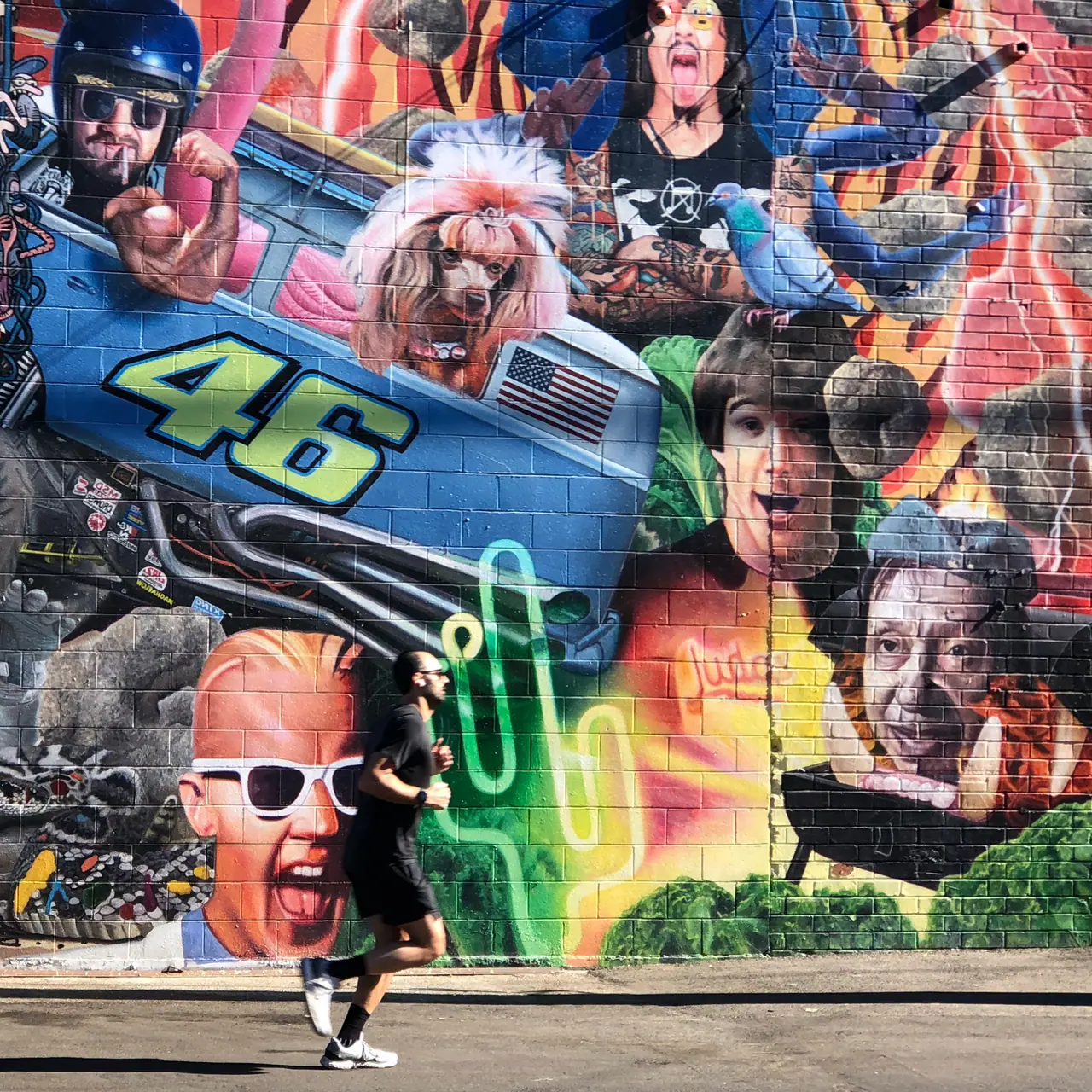 A pedestrian passing a colorful mural.