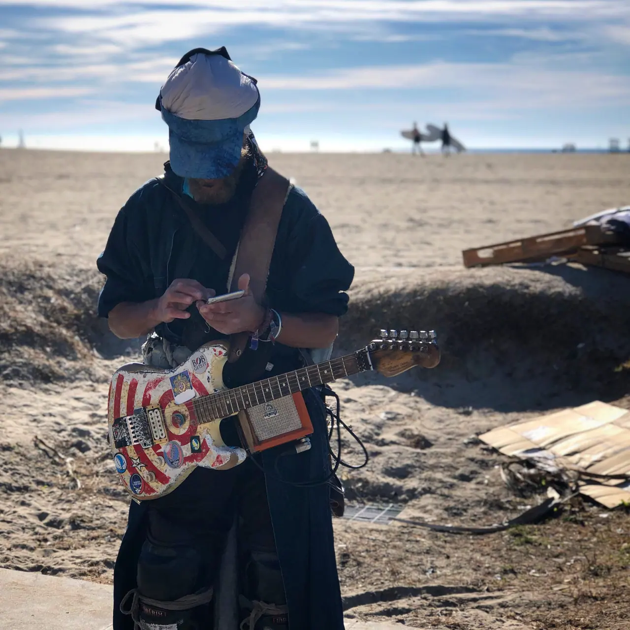 A guitarist checking a phone at Venice Beach.