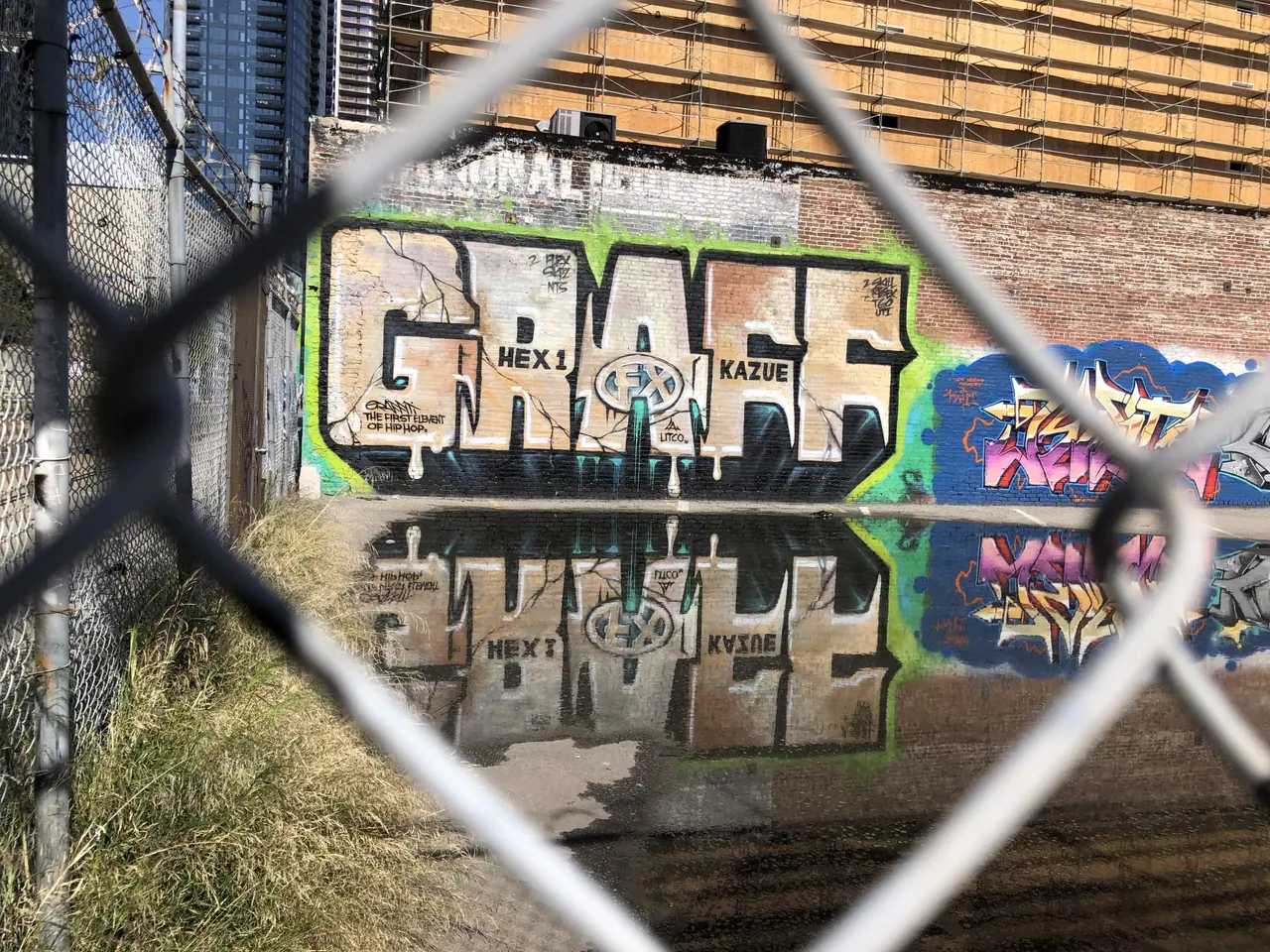 Graffiti reflected in water behind a chain-link fence in Boyle Heights.