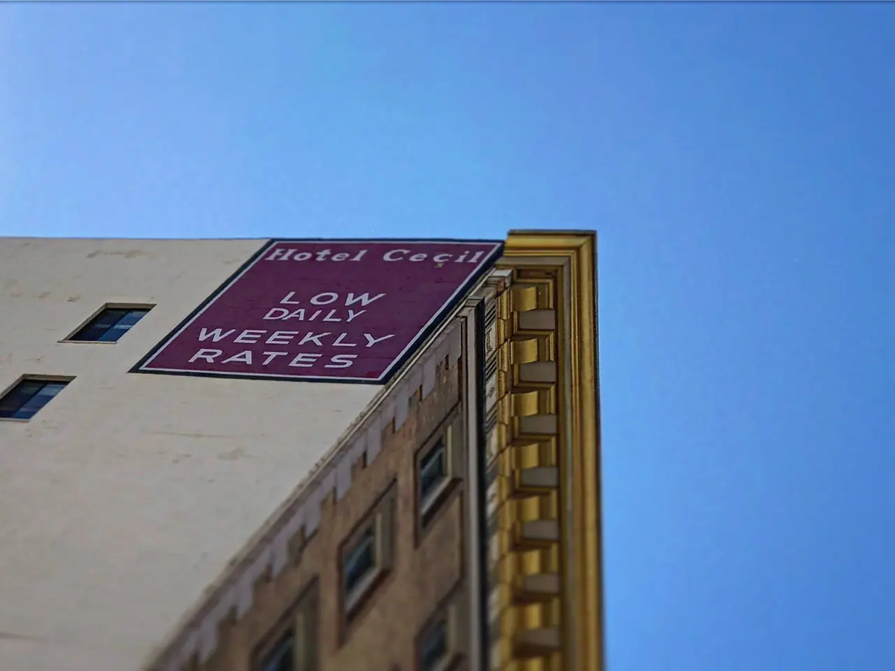 The Hotel Cecil facade beneath a blue sky.