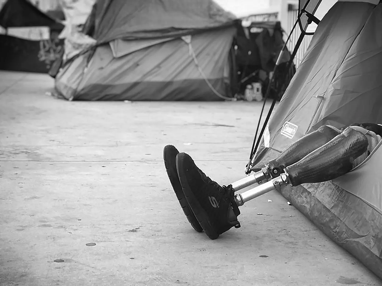 A prosthetic leg resting beside a sidewalk tent.