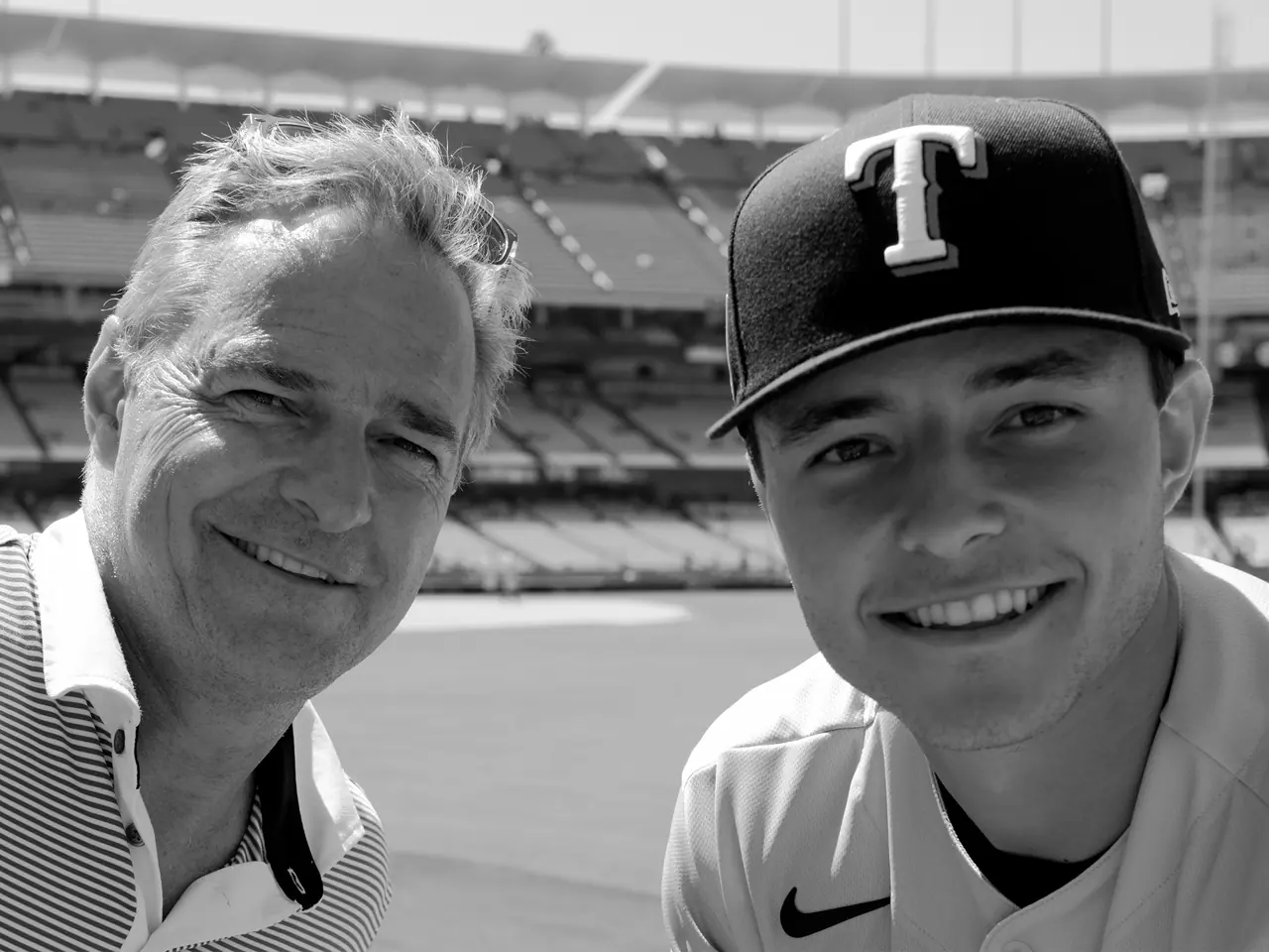 A baseball player and a fan posing together beside the field.