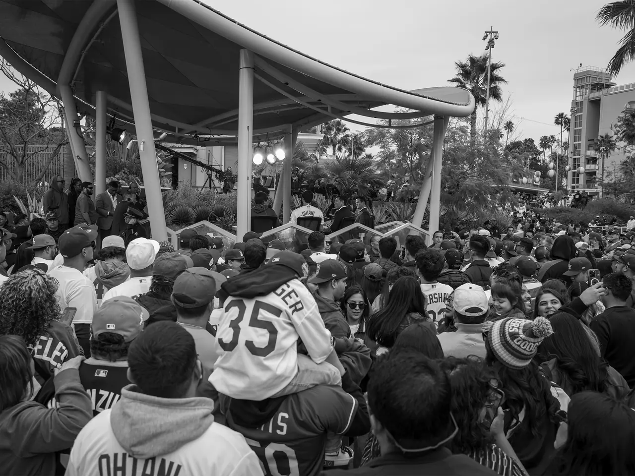 A child on an adult's shoulders among a crowd at a stadium gathering.