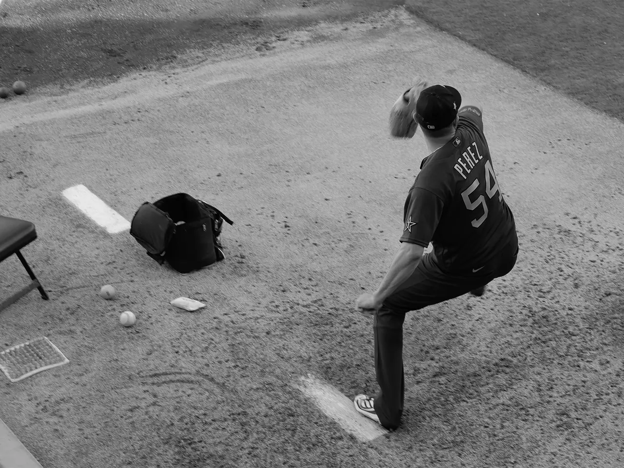 A baseball pitcher warming up in the bullpen, seen from above.