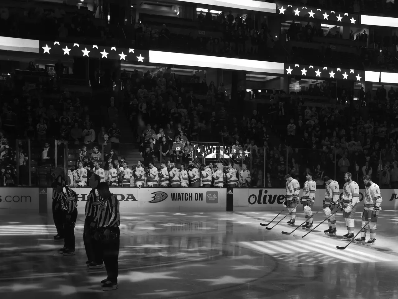 Hockey players and an official gathered beneath arena lights before a game.