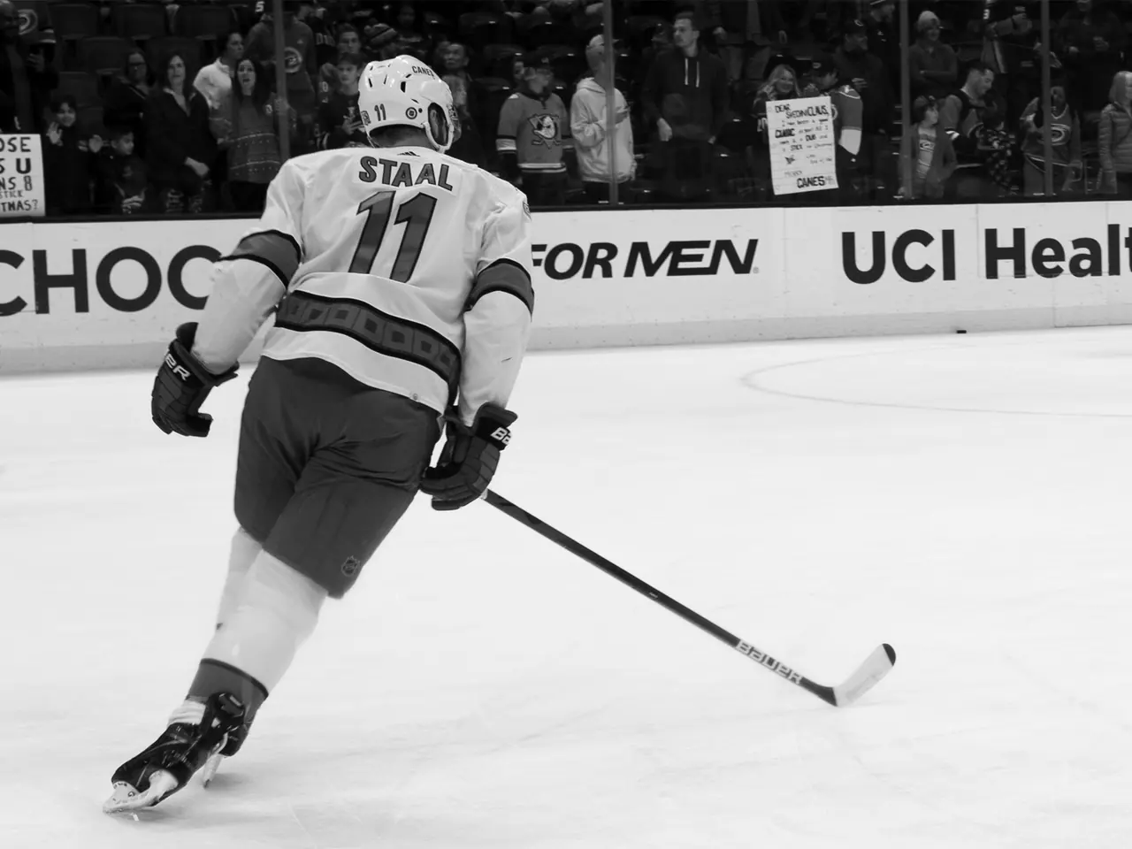 A hockey player skating across the ice with a stick extended.