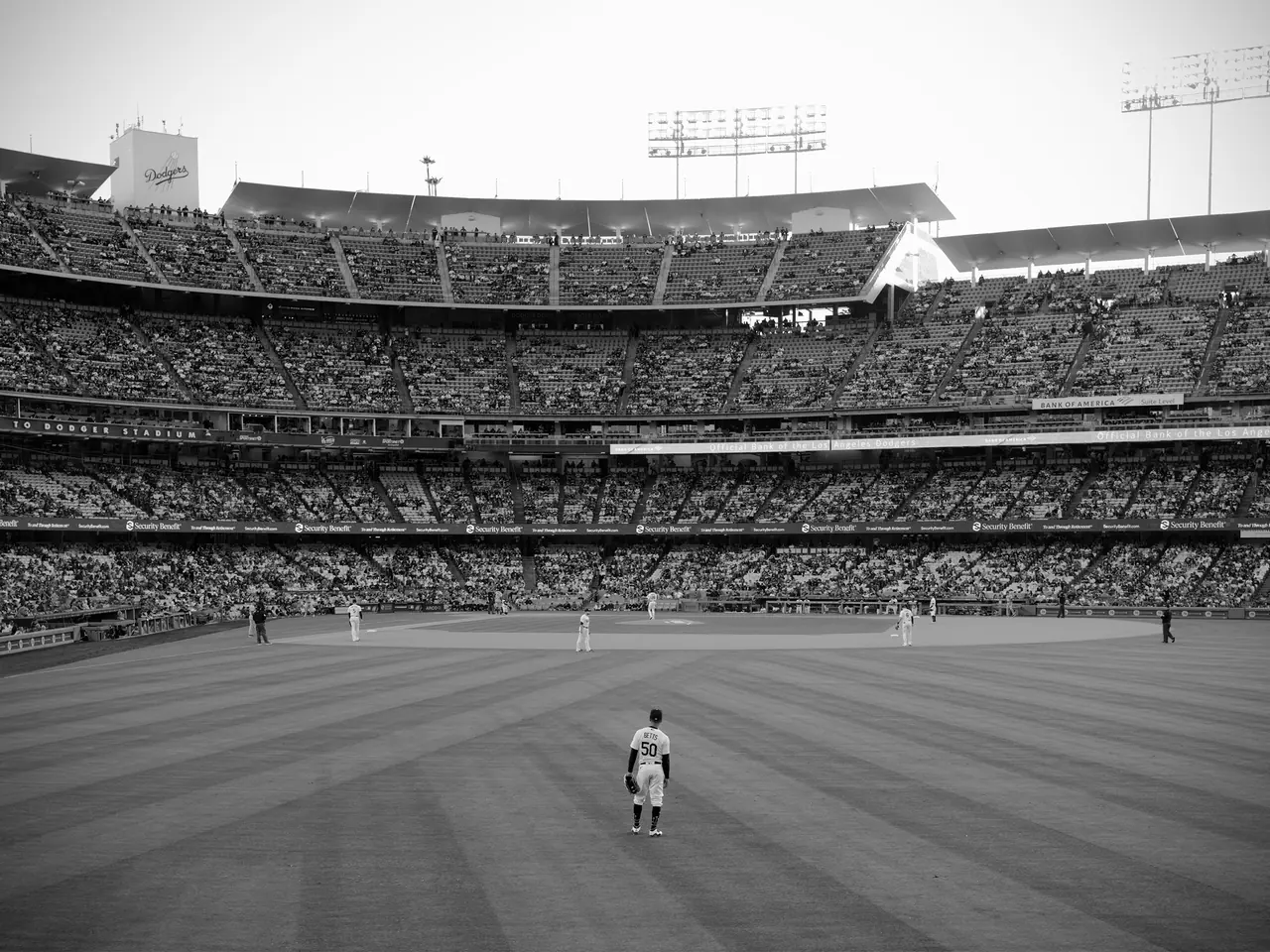 An outfielder standing before a full grandstand at Dodger Stadium.