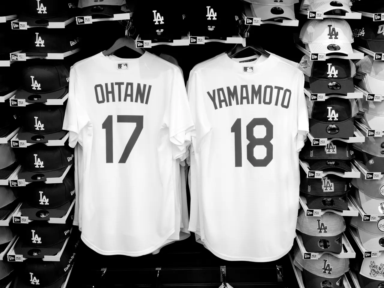 Two Dodgers jerseys displayed among rows of team caps.
