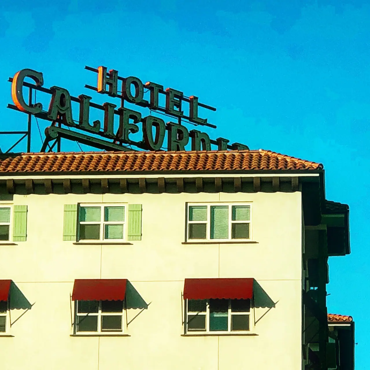 The Hotel California rooftop sign above a pale facade.