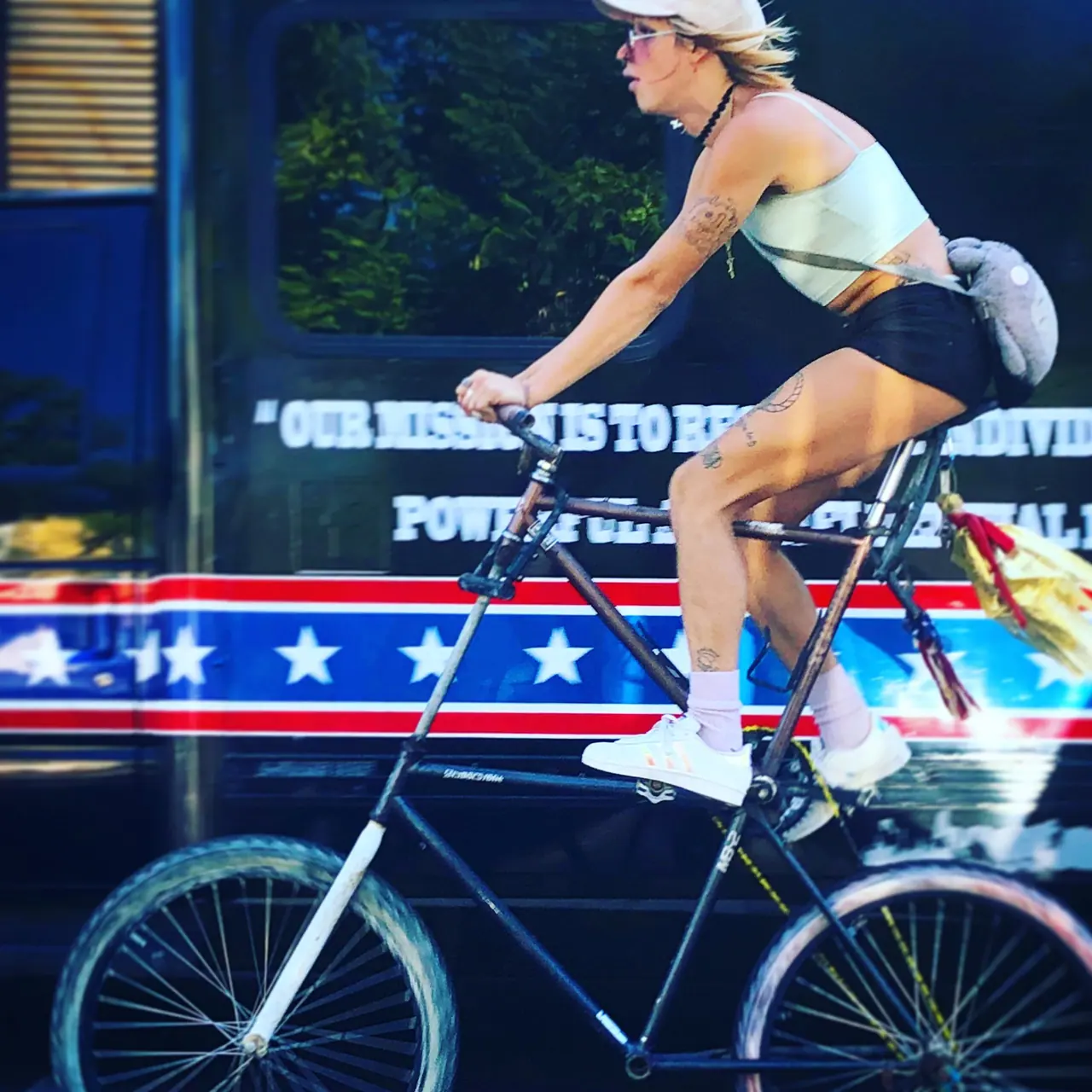 A cyclist riding a tall bicycle past a bus.