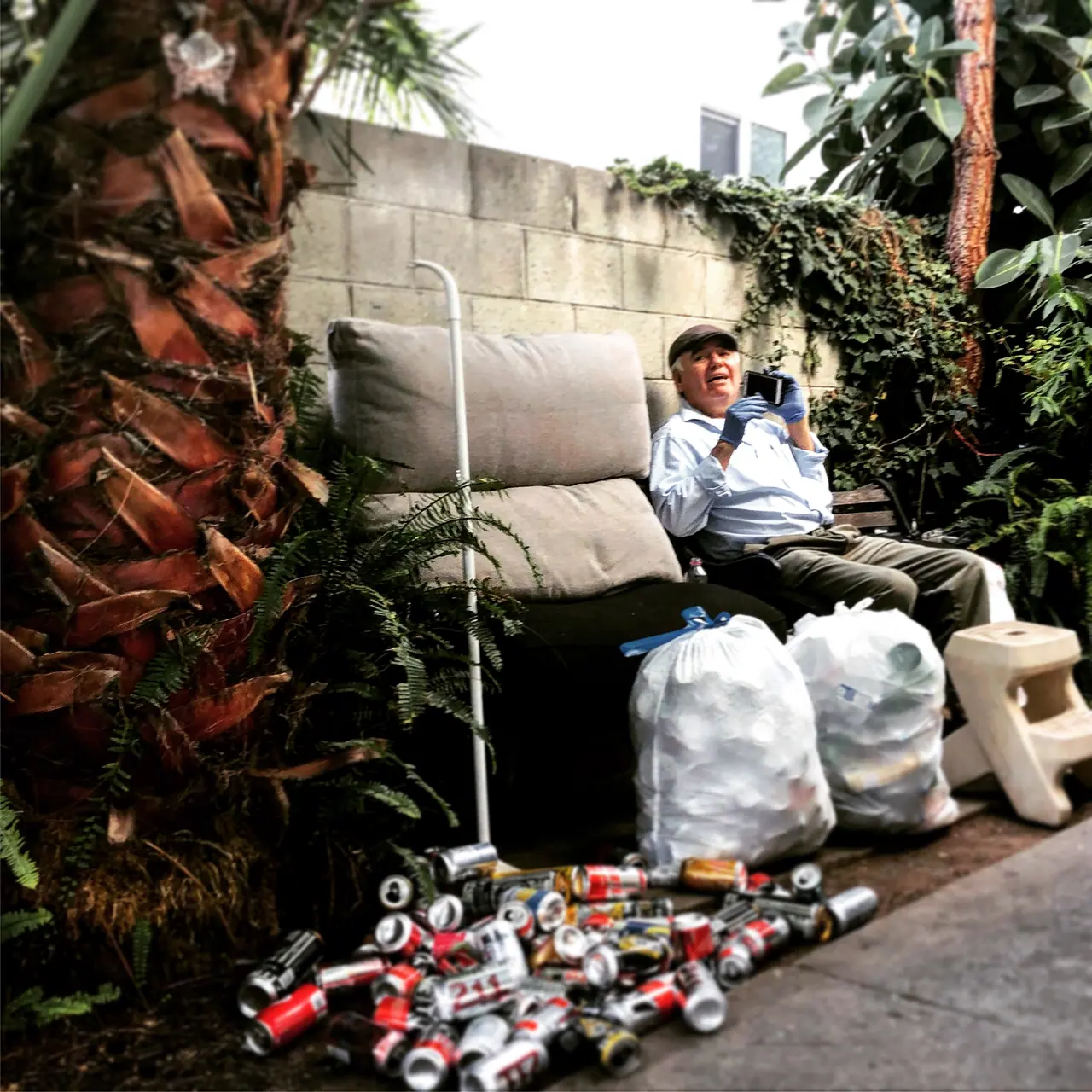 A seated street portrait beside a collection of cans.