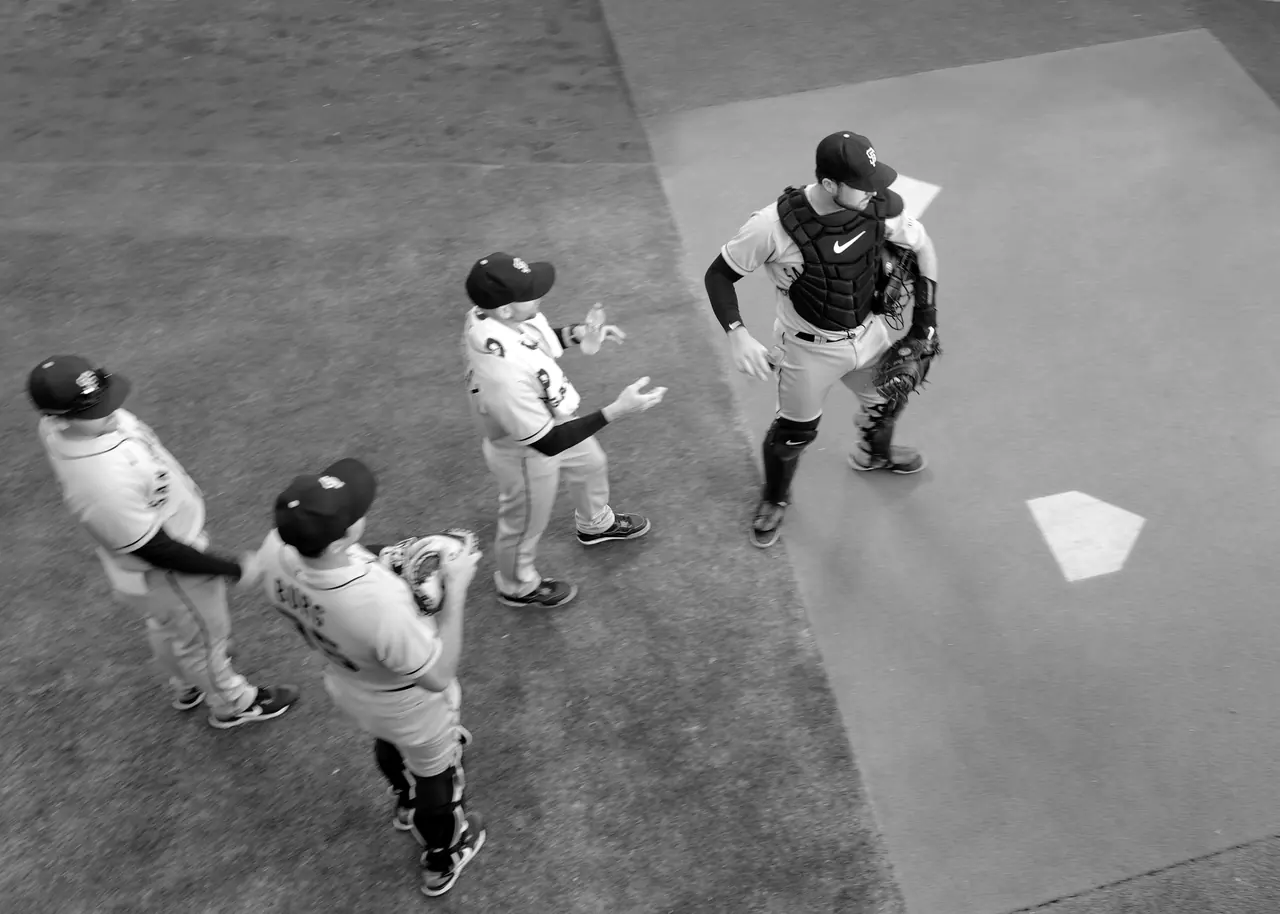 Players and a catcher gathered beside home plate, seen from above.