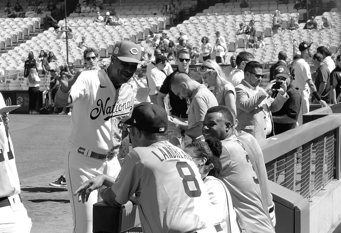 Baseball players talking with fans beside a stadium railing.