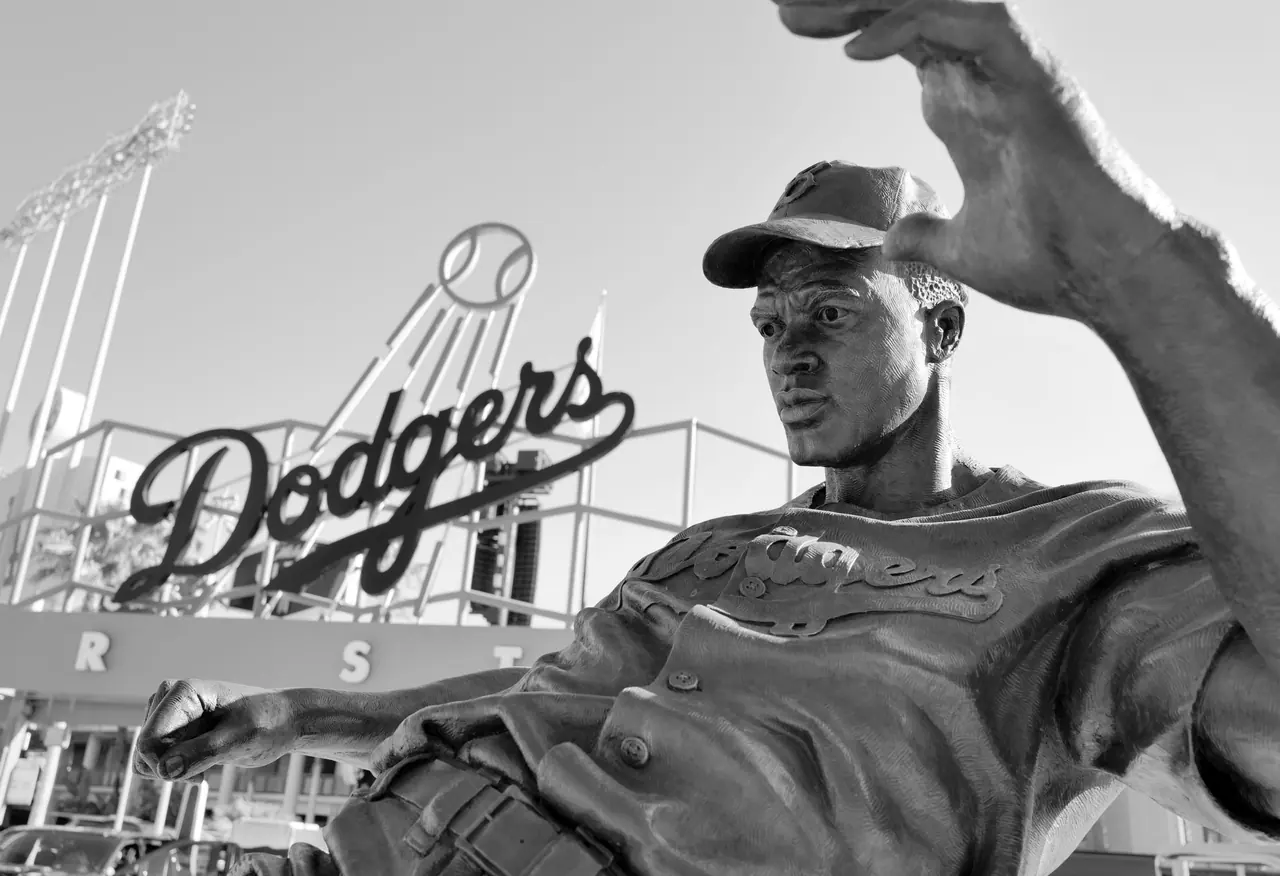 A bronze baseball player statue beneath the Dodgers sign.