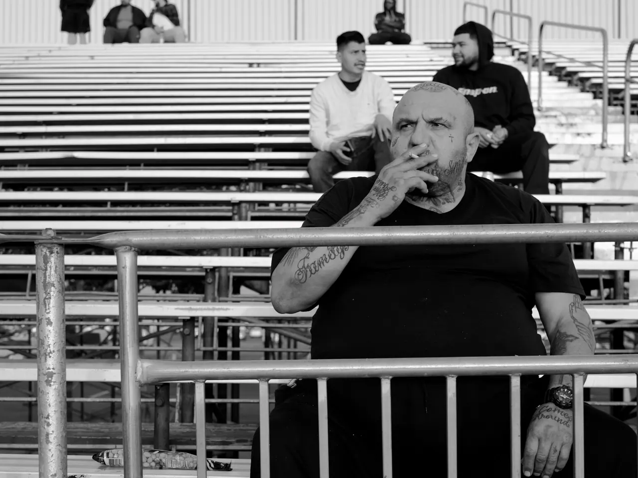 A spectator seated behind metal railings in the Irwindale grandstand.