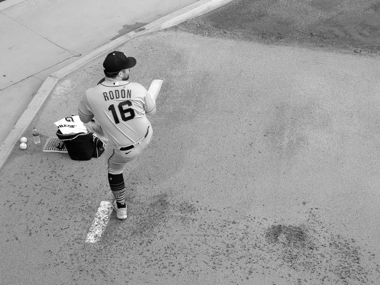 A pitcher lifting a leg during a bullpen warm-up.