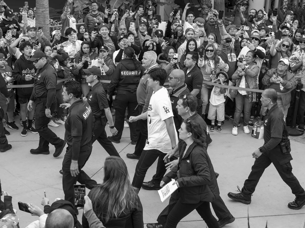 A baseball player and security staff moving through a crowd of fans.