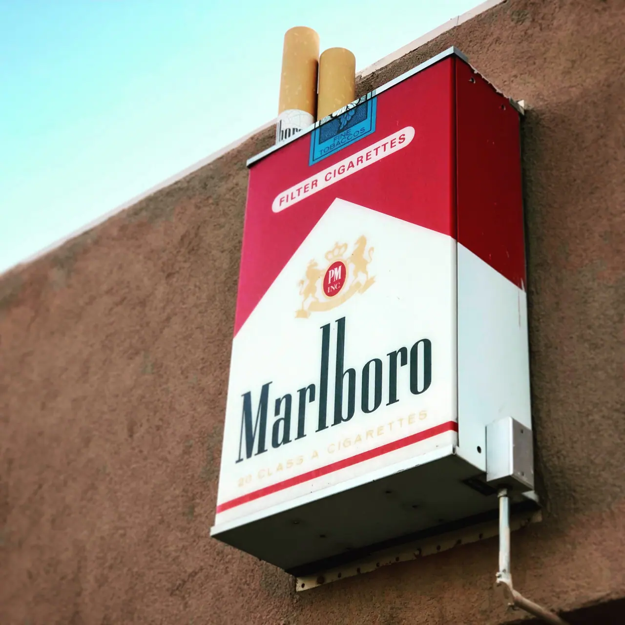 An oversized cigarette-pack sign on a stucco wall.