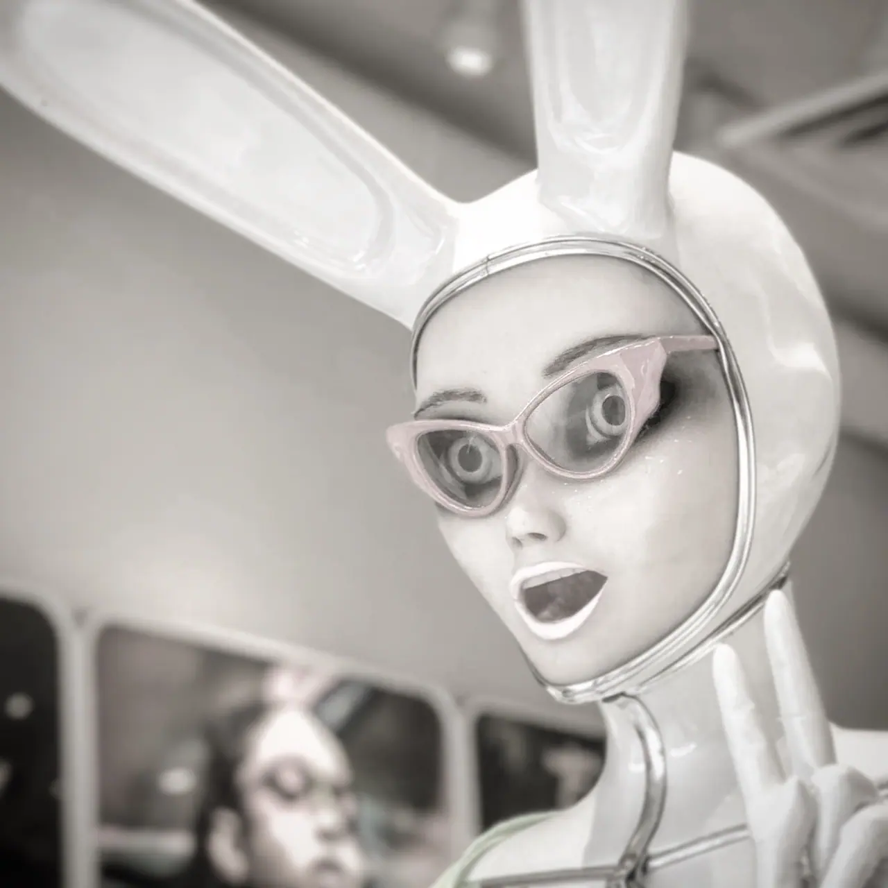 A white rabbit mannequin wearing cat-eye glasses in a shop window.
