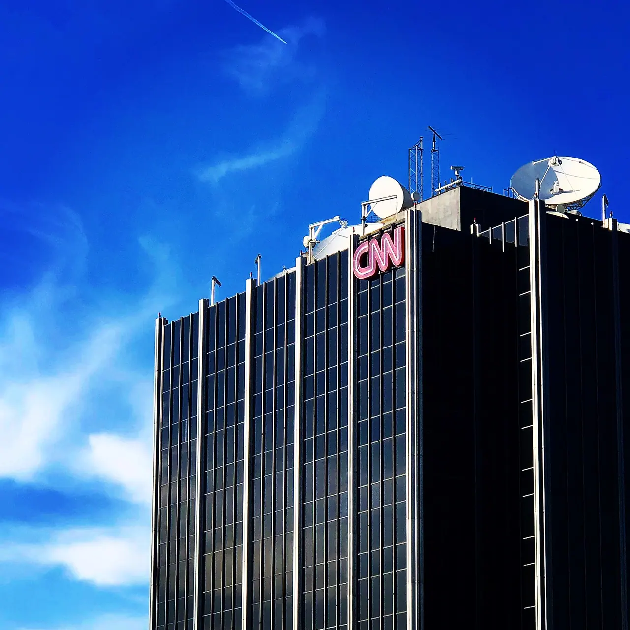 The CNN building beneath a vivid blue sky.
