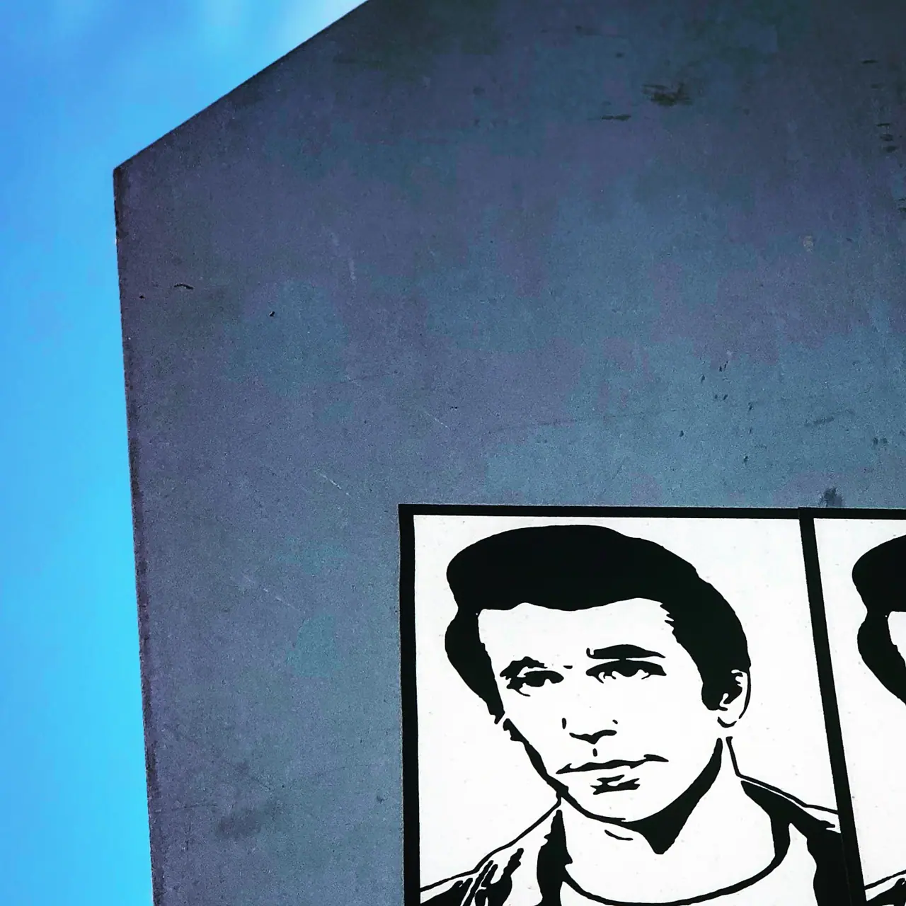 A black-and-white portrait mural against a blue wall.